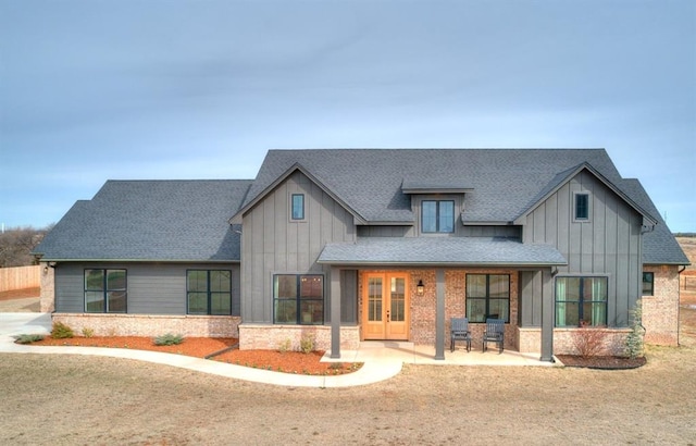 modern inspired farmhouse featuring a patio area, a shingled roof, board and batten siding, and french doors