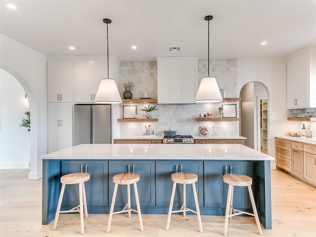 kitchen featuring arched walkways, open shelves, and freestanding refrigerator