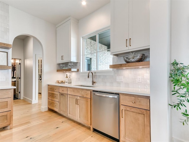 kitchen with a sink, tasteful backsplash, light countertops, and stainless steel dishwasher