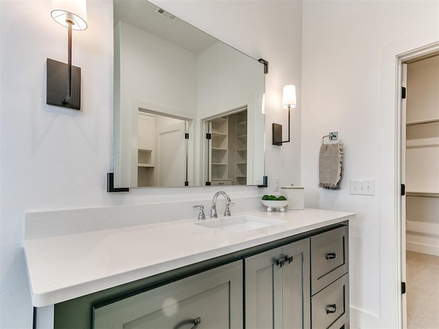 bathroom featuring visible vents, a walk in closet, and vanity