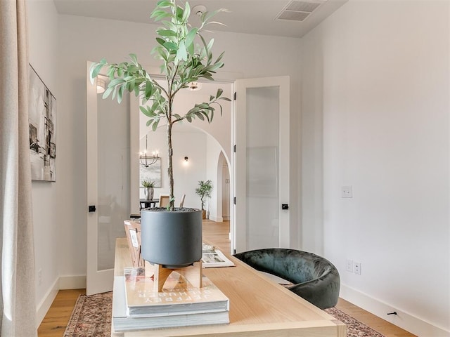 home office with arched walkways, light wood-style flooring, visible vents, and baseboards