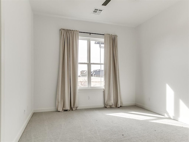 carpeted empty room featuring a ceiling fan, visible vents, and baseboards