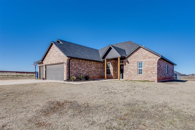 single story home with a garage, roof with shingles, concrete driveway, and brick siding