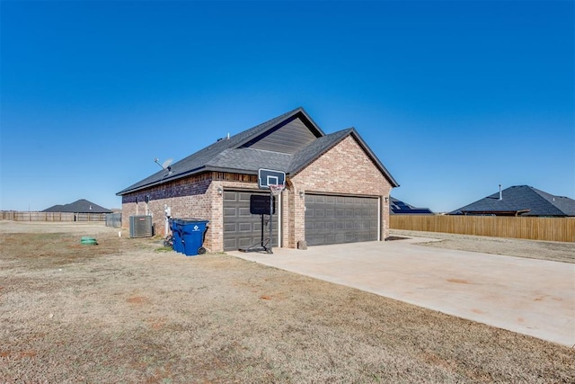 view of side of home with concrete driveway, brick siding, fence, and central air condition unit