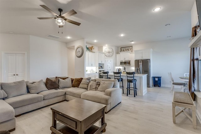 living area featuring ceiling fan, light wood-type flooring, visible vents, and recessed lighting