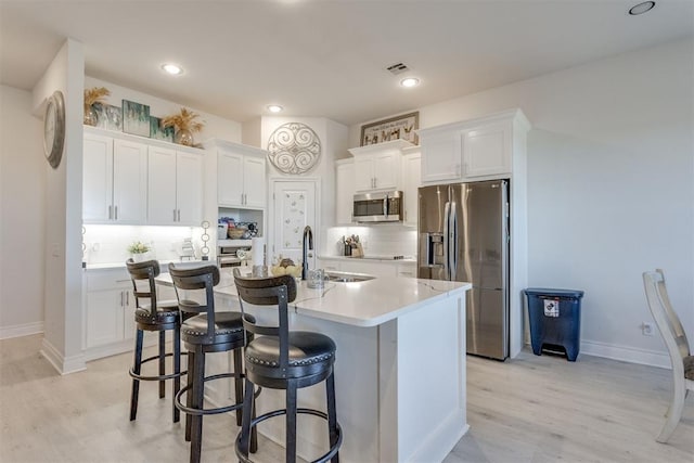 kitchen featuring stainless steel appliances, visible vents, an island with sink, and white cabinetry