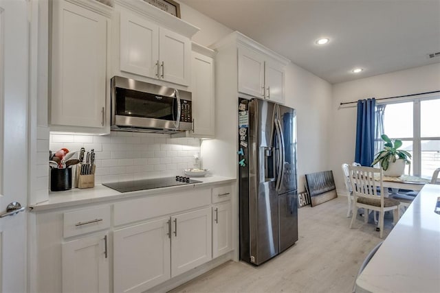 kitchen featuring light wood finished floors, stainless steel appliances, light countertops, decorative backsplash, and white cabinets