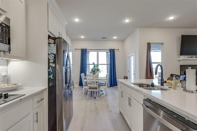 kitchen with appliances with stainless steel finishes, light wood-style floors, white cabinetry, a sink, and recessed lighting