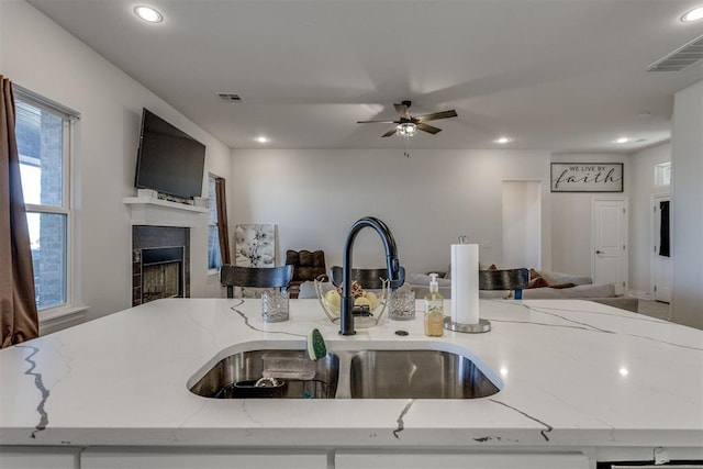 kitchen with open floor plan, a fireplace, a sink, and visible vents