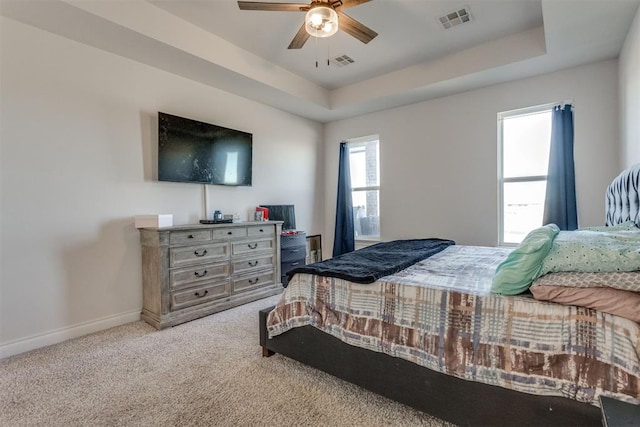 carpeted bedroom featuring a raised ceiling, visible vents, and baseboards