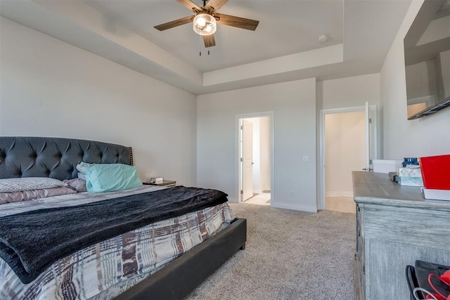 bedroom featuring baseboards, a tray ceiling, a ceiling fan, and light colored carpet