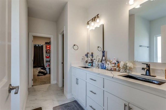 bathroom with marble finish floor, a sink, a spacious closet, and double vanity