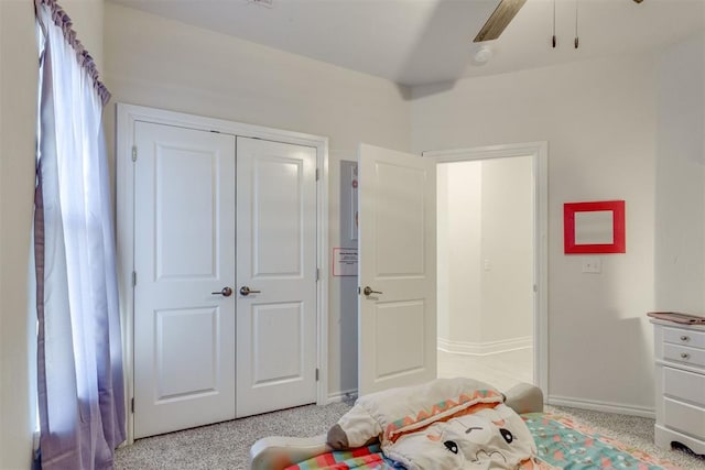 bedroom with a ceiling fan, a closet, light colored carpet, and baseboards