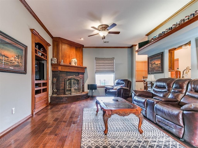 living room with dark wood-style flooring, visible vents, ornamental molding, a ceiling fan, and a brick fireplace