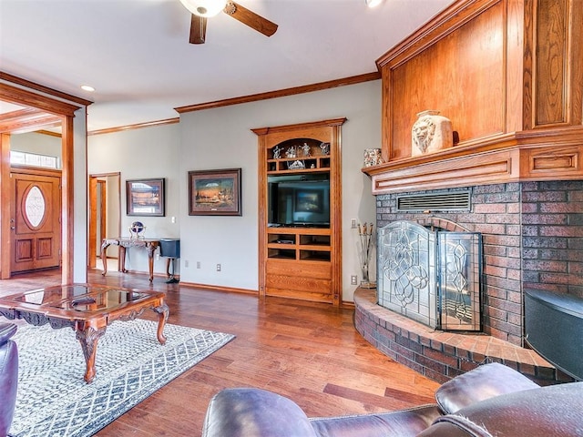 living room with ornamental molding, a fireplace, wood finished floors, and baseboards