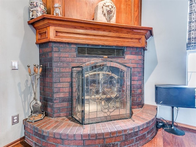 details featuring a brick fireplace, baseboards, and wood finished floors