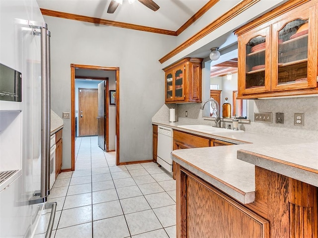 kitchen featuring tasteful backsplash, brown cabinetry, ornamental molding, white dishwasher, and a sink