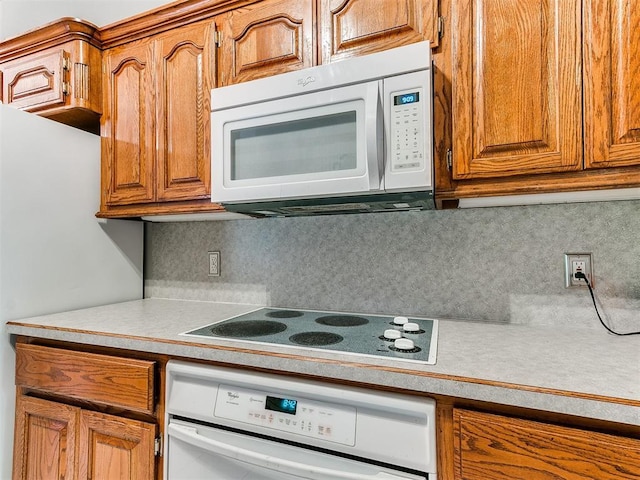 kitchen featuring light countertops, white appliances, brown cabinets, and backsplash