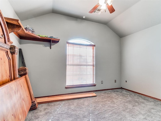 carpeted empty room with visible vents, vaulted ceiling, baseboards, and ceiling fan