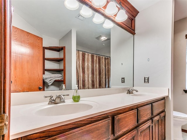 bathroom featuring visible vents, a sink, toilet, and double vanity