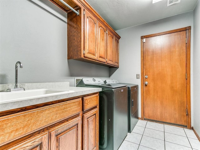 laundry area featuring cabinet space, light tile patterned floors, washer and dryer, and a sink