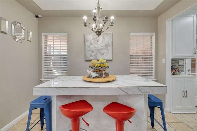 kitchen featuring a breakfast bar, light tile patterned floors, hanging light fixtures, light stone countertops, and a chandelier