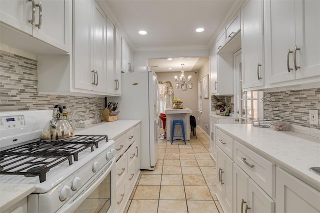 kitchen featuring white appliances, light tile patterned floors, decorative backsplash, white cabinetry, and a notable chandelier