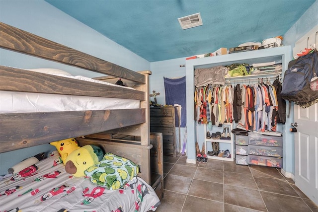 bedroom with a closet, visible vents, and tile patterned floors