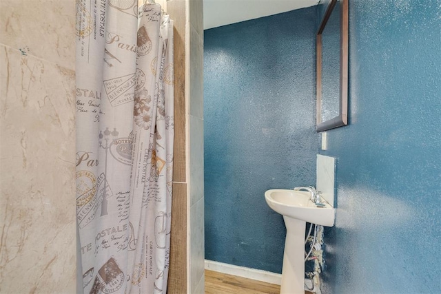 full bathroom with a shower with curtain, baseboards, and wood finished floors