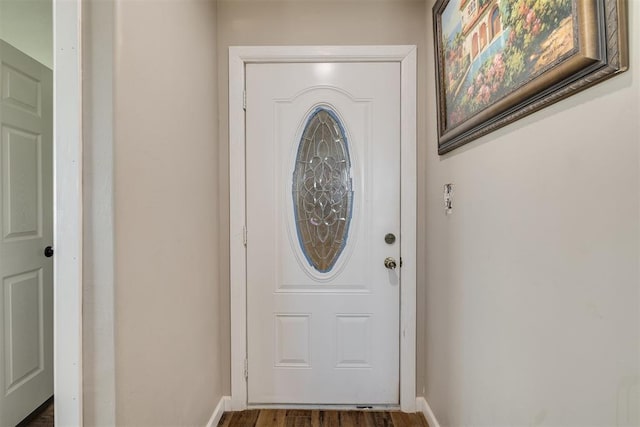 doorway featuring baseboards and wood finished floors