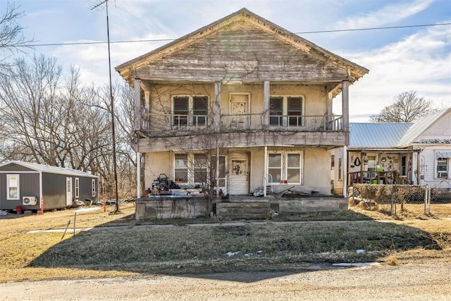 view of front of house featuring a porch, fence, a balcony, and stucco siding