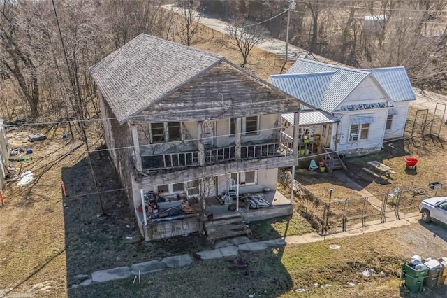 rear view of house featuring metal roof, a balcony, a wooden deck, and fence