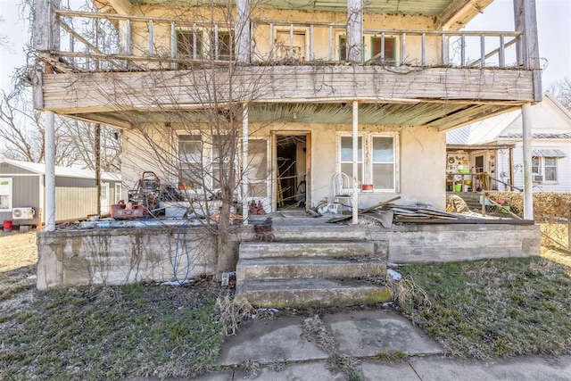 view of front of house with covered porch, a balcony, and stucco siding