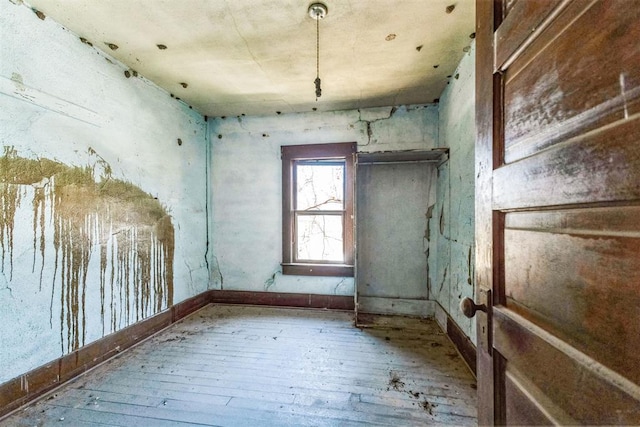 unfurnished room featuring wood-type flooring and baseboards