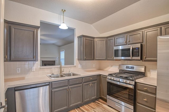 kitchen featuring appliances with stainless steel finishes, vaulted ceiling, a sink, and light countertops