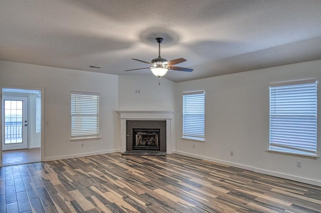 unfurnished living room featuring a textured ceiling, a fireplace, wood finished floors, and baseboards