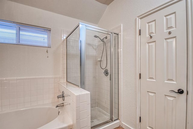 bathroom with a textured wall, a shower stall, and a bath