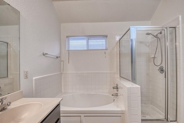 bathroom with a textured wall, a shower stall, a bath, and vanity