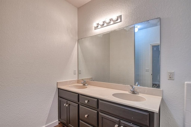 full bath featuring a textured wall, a sink, and double vanity