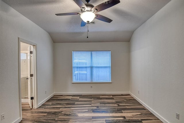 empty room featuring lofted ceiling, a textured ceiling, baseboards, and wood finished floors