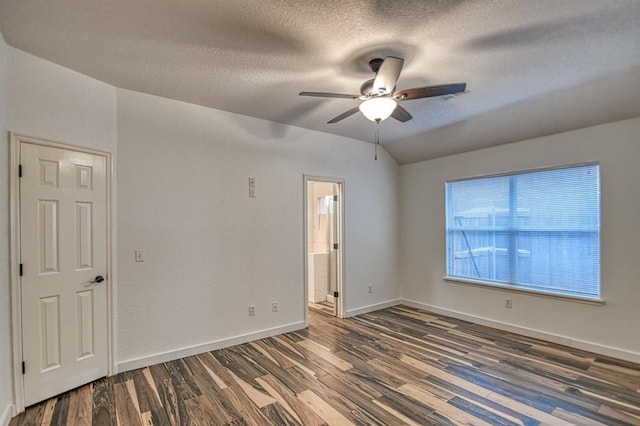 empty room featuring lofted ceiling, a textured ceiling, baseboards, and wood finished floors