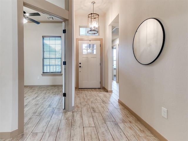 entrance foyer featuring baseboards, ceiling fan with notable chandelier, visible vents, and wood finish floors