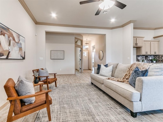 living area featuring visible vents, baseboards, ceiling fan, ornamental molding, and light wood-type flooring