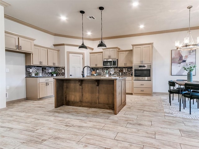 kitchen featuring stainless steel appliances, visible vents, backsplash, an island with sink, and a chandelier