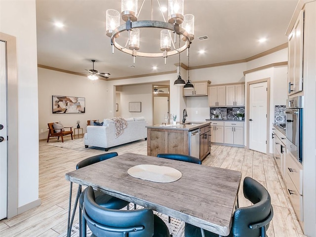 dining area with ceiling fan with notable chandelier, visible vents, baseboards, ornamental molding, and light wood finished floors