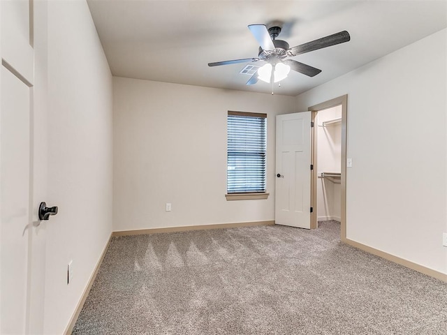 unfurnished bedroom featuring a ceiling fan, baseboards, a walk in closet, and carpet flooring