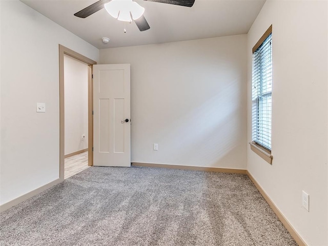 empty room featuring light carpet, a ceiling fan, and baseboards