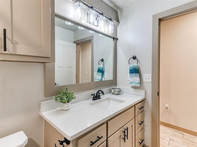 bathroom with wood finished floors, vanity, toilet, and baseboards