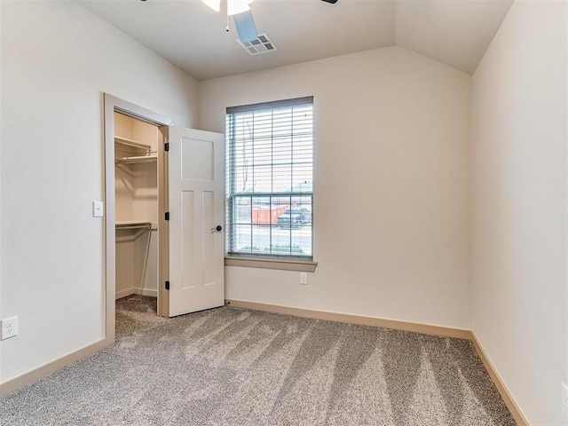 unfurnished bedroom featuring baseboards, visible vents, a spacious closet, vaulted ceiling, and carpet flooring