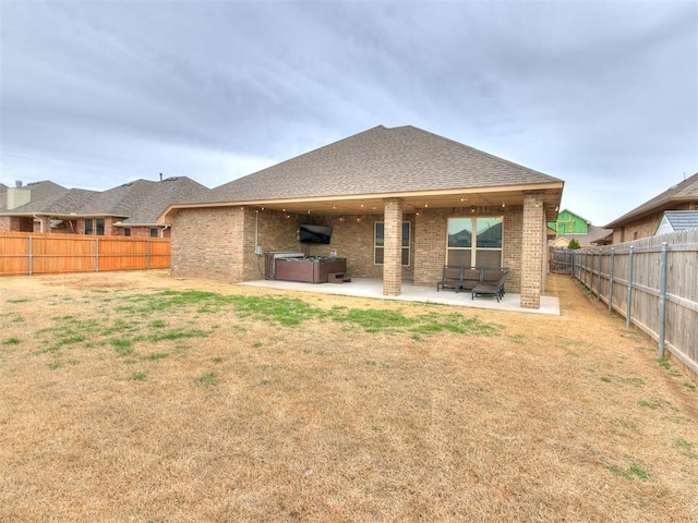 rear view of house with a yard, a patio, brick siding, and a fenced backyard